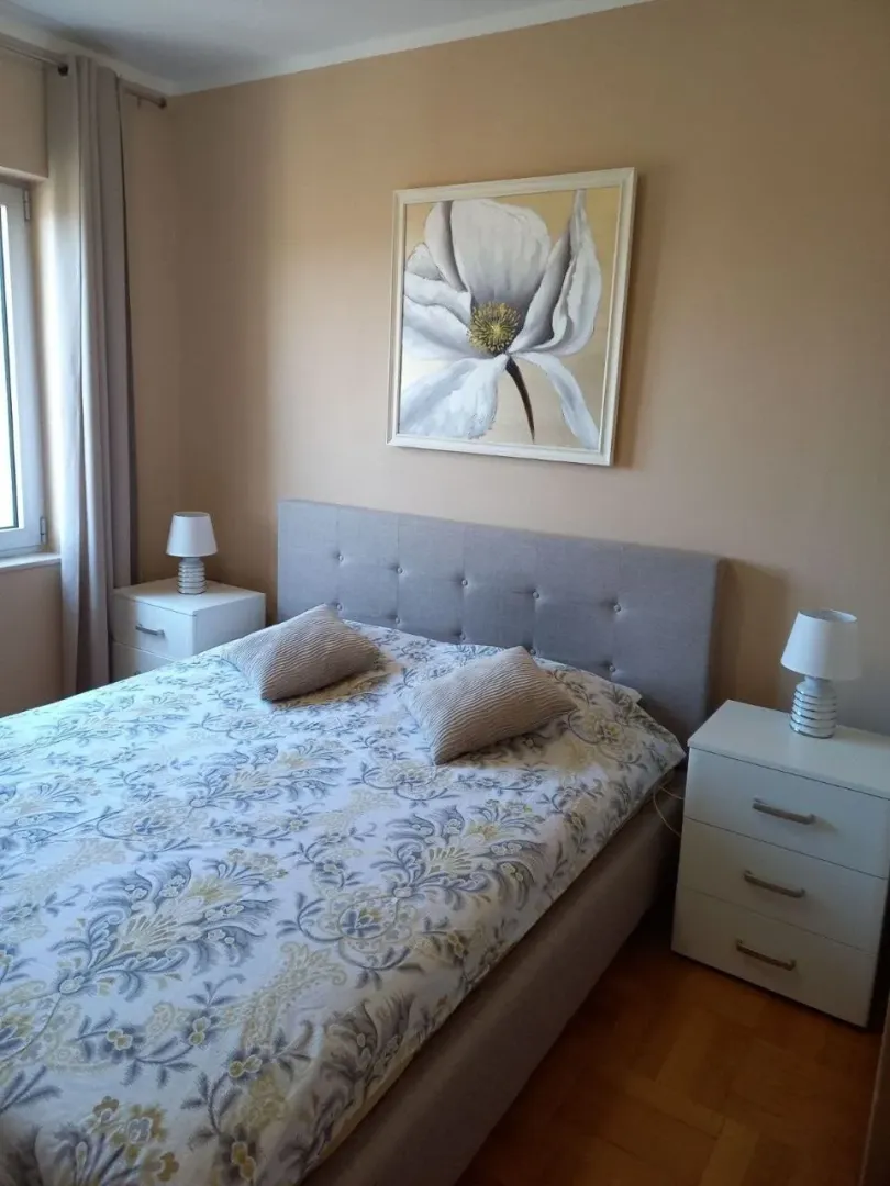 Furnished bedroom with a double bed, bedside tables, and a painting on the wall.