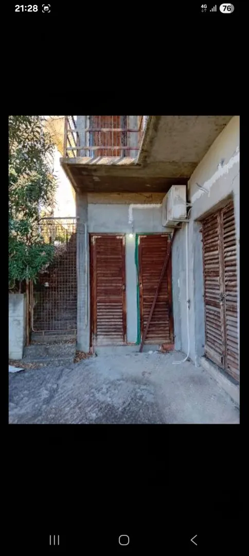 Eksterijer kuće sa spoljnim stepeništem i drvenim vratima.