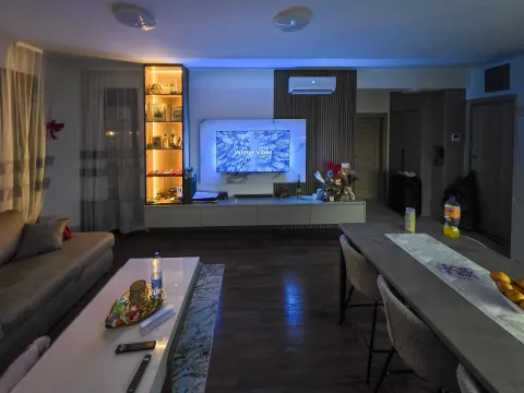 Dnevna soba sa garniturom, TV-om i trpezarijskim stolom u večernjoj atmosferi. - image 4