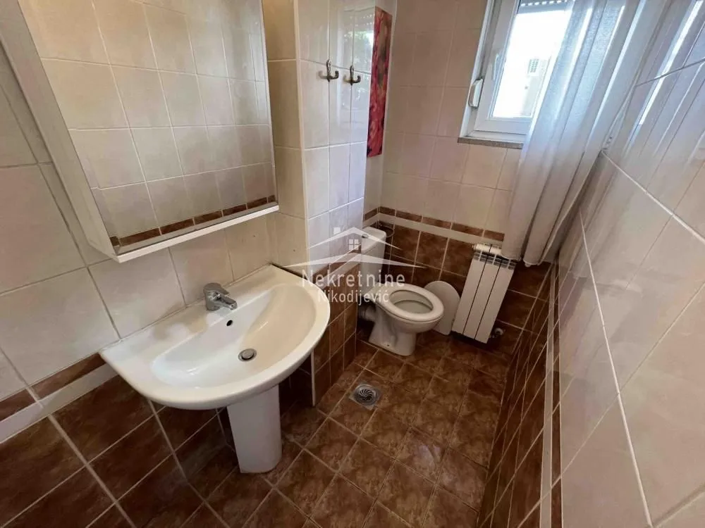 Small bathroom with a sink, toilet, and window.