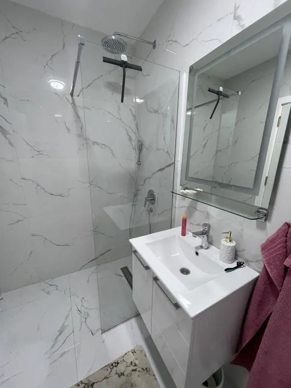 Modern bathroom with a walk-in shower and marble-effect tiles.
