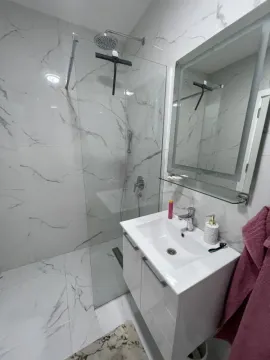 Modern bathroom with a walk-in shower and marble-effect tiles. - image 8
