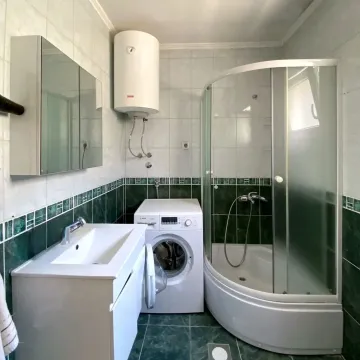 Bathroom with a shower cabin, washbasin, washing machine, and water heater. - image 3