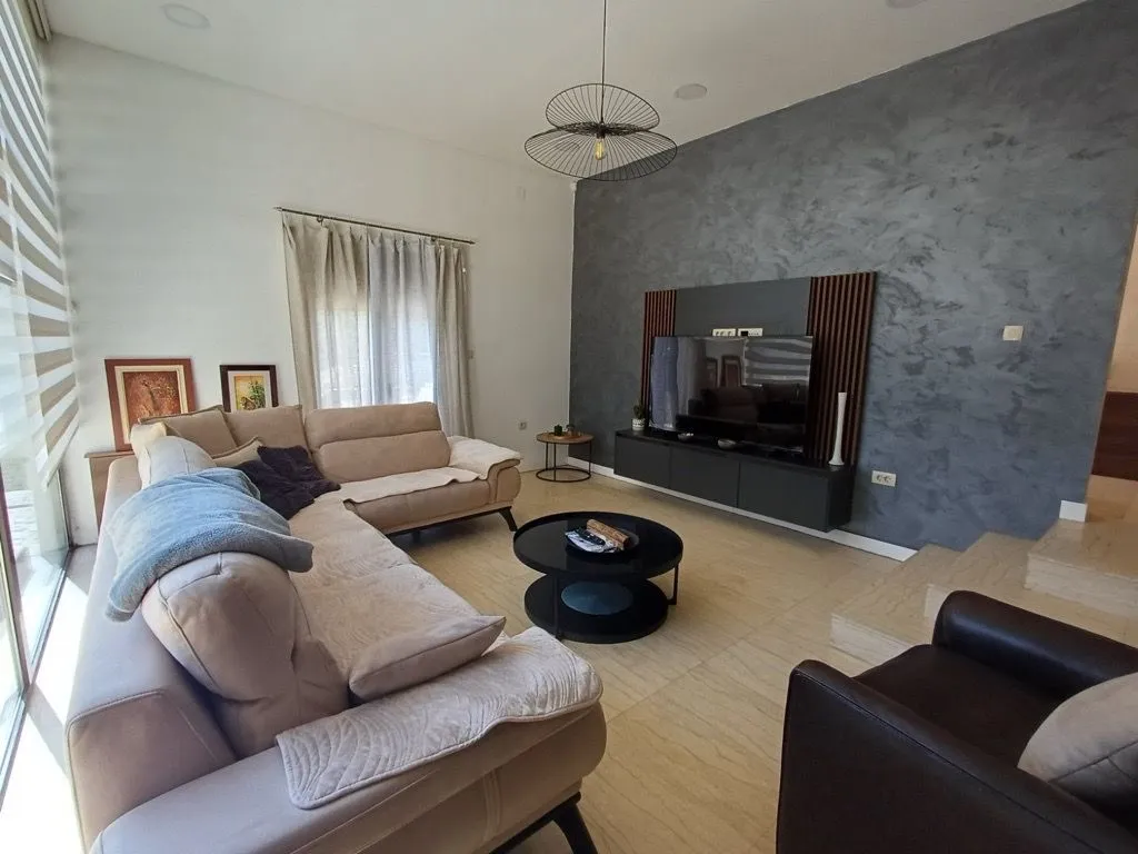 Spacious living room with a sectional sofa, TV unit, and decorative accent wall.