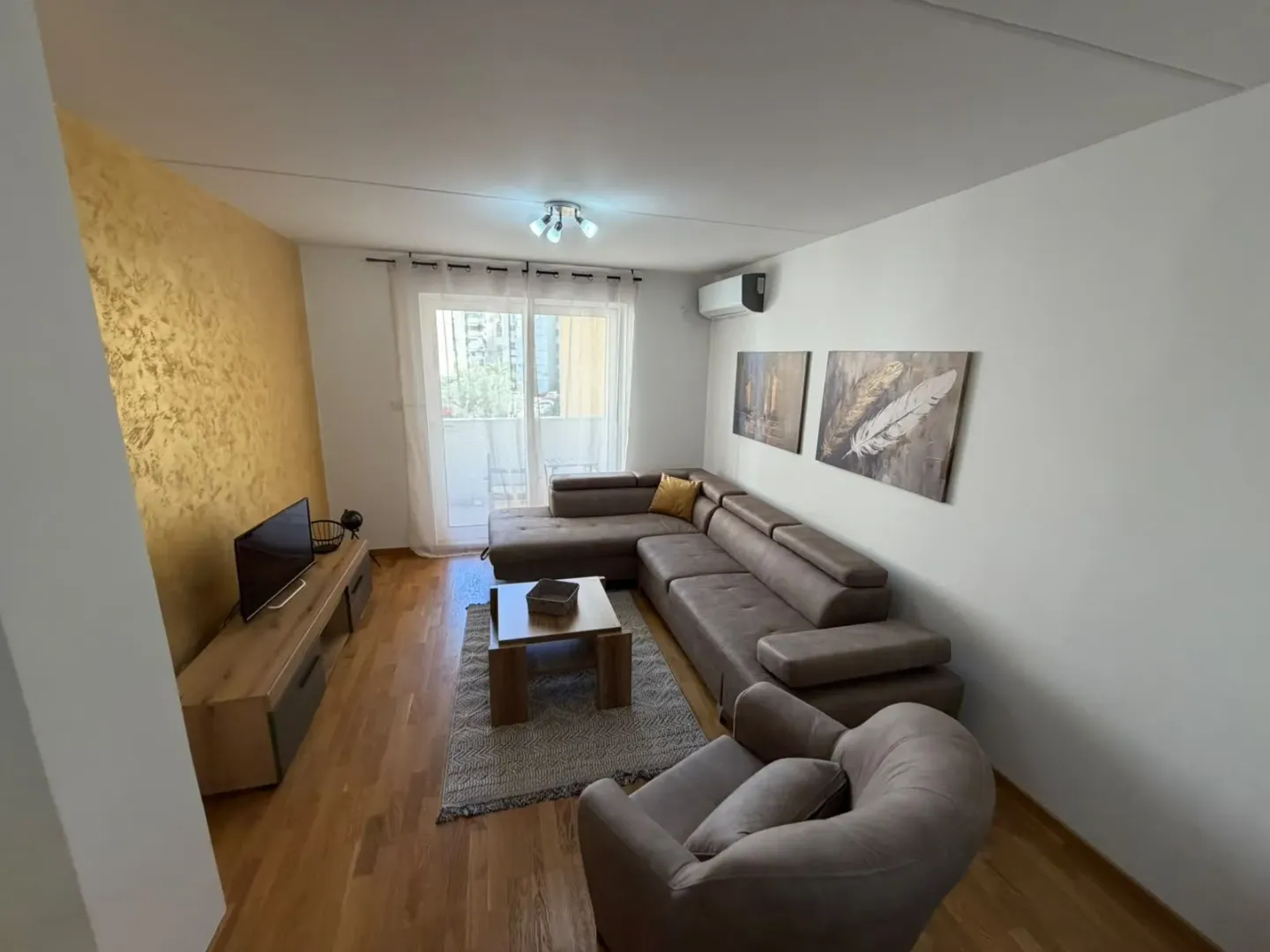 Living room with a sectional sofa, TV, and balcony access.
