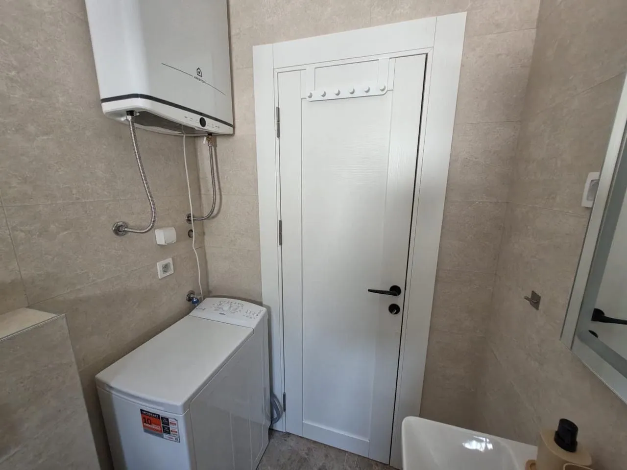 Bathroom equipped with plumbing fixtures, a washing machine, and a water heater.