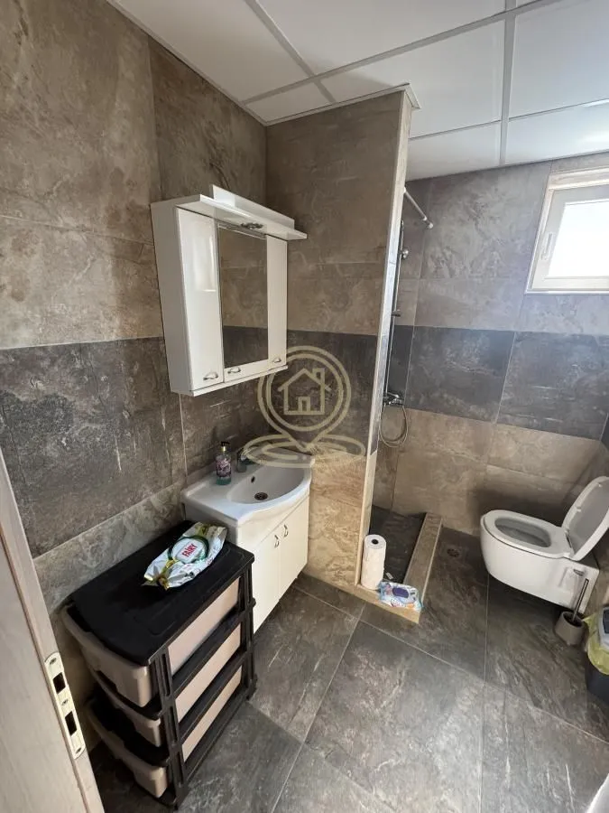 Kupatilo obloženo keramičkim pločicama sa umivaonikom, ogledalom i wc šoljom.