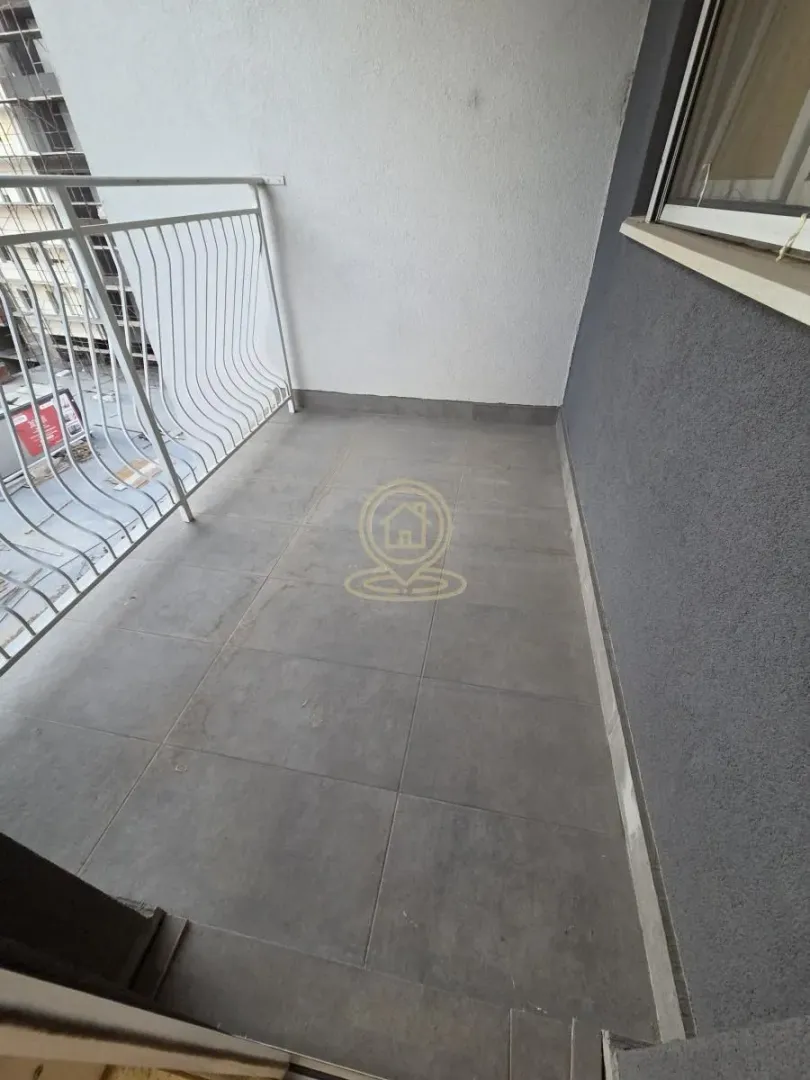 Nenamesteni balkon sa podnim pločicama i metalnom ogradom.