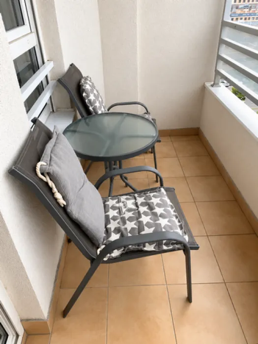 Small furnished balcony with a table and two chairs.