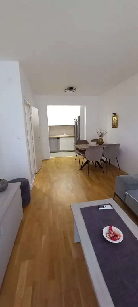 Bright living room with a dining area and kitchen in the background.
