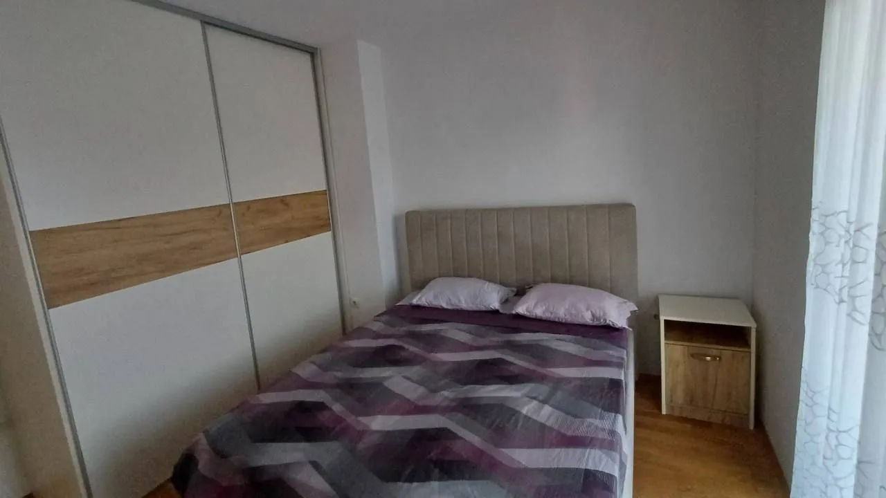 Spavaća soba sa bračnim krevetom, ugradnim plakarom i noćnim stočićem.