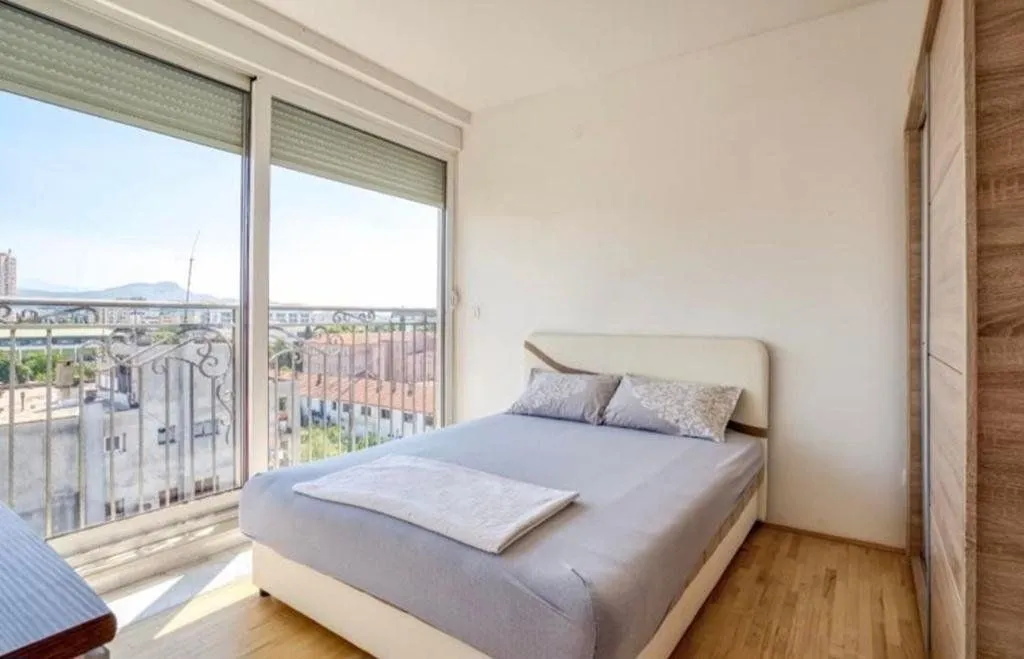 Bright bedroom with a double bed, wardrobe, and large balcony doors.