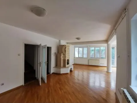 Spacious living room with wooden flooring, a fireplace, and large windows. - image 6