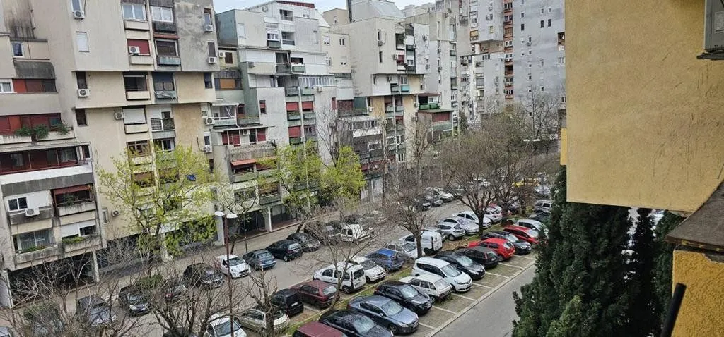 Pogled sa terase na okolne stambene zgrade i parking.