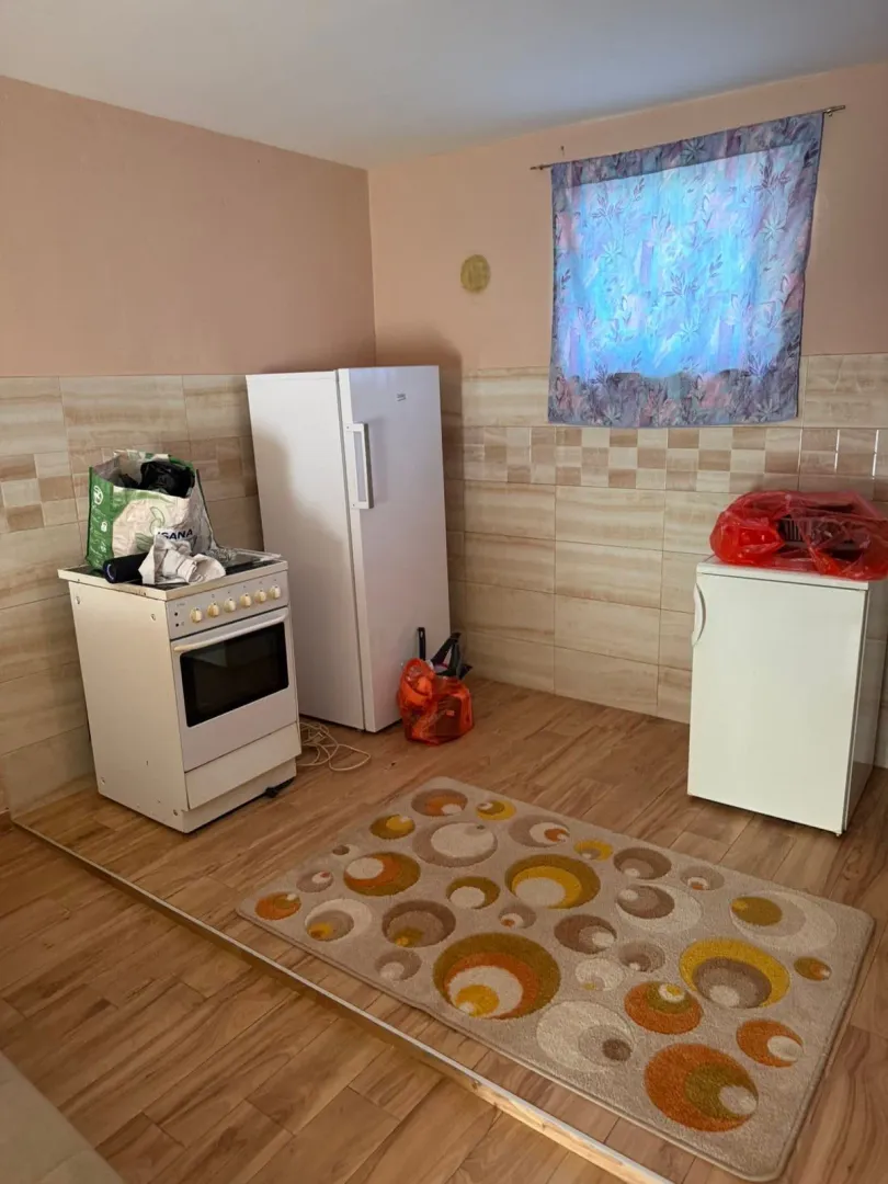 Small kitchen with a stove, refrigerator, and ceramic wall tiles.