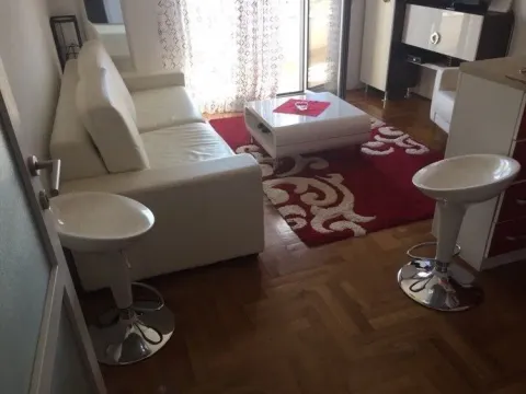 Dnevna soba sa bijelom kožnom garniturom, crvenim tepihom i barskim stolicama. - image 2
