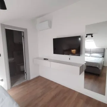 Modern bedroom with a double bed, wall-mounted TV, and an ensuite bathroom. - image 12