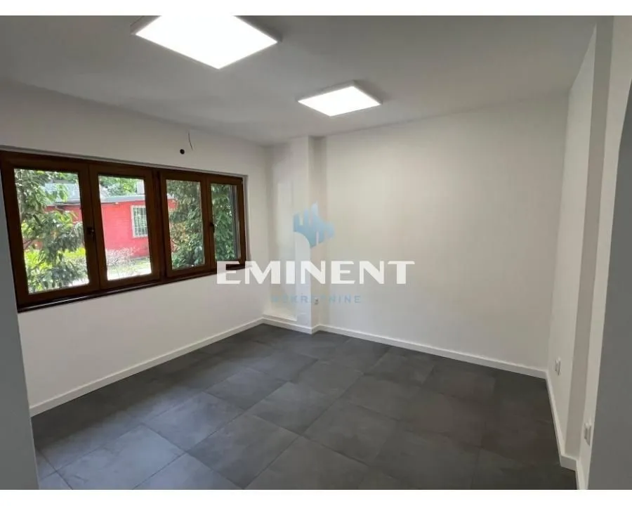 Empty room with dark floor tiles and wooden window frames.
