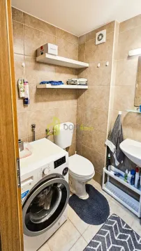 Small tiled bathroom with a toilet, washbasin, and washing machine. - image 3
