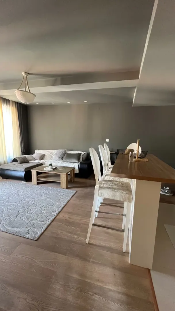 Living room with a sofa and a bar counter with bar stools.