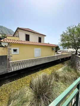 Exterior view of a house with a yellow facade and a terrace by a stream. - image 3