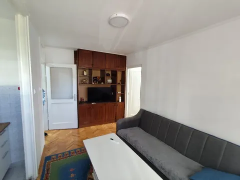 Dnevna soba sa sivom sofom, bijelim stočićem i drvenim namještajem. - image 7