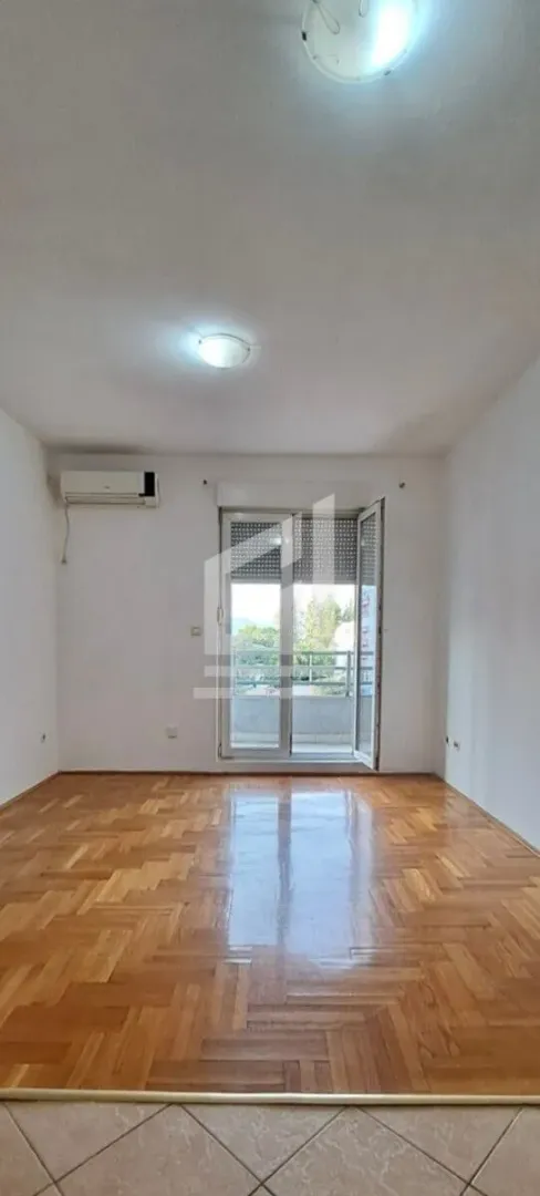 Prazna soba sa parketom i izlazom na terasu.
