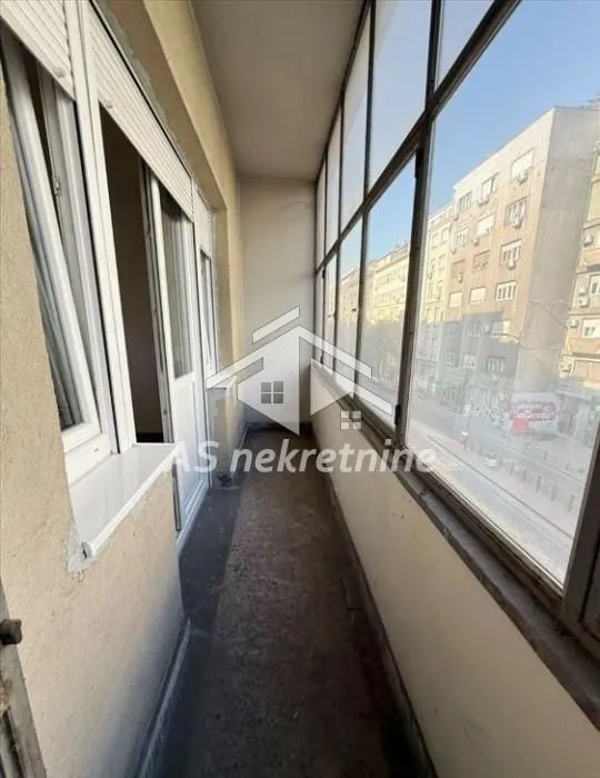 Enclosed balcony with a view of the street and surrounding buildings.