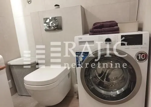 Smaller bathroom with a washing machine and toilet.