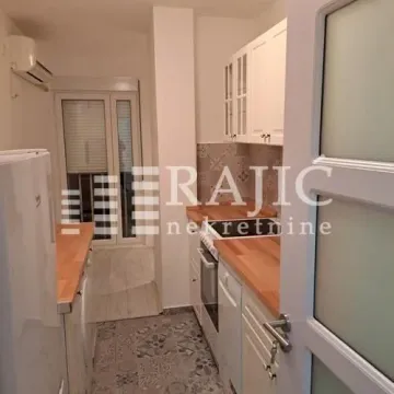 A view of a small kitchen with white cabinets and a wooden countertop. - image 9