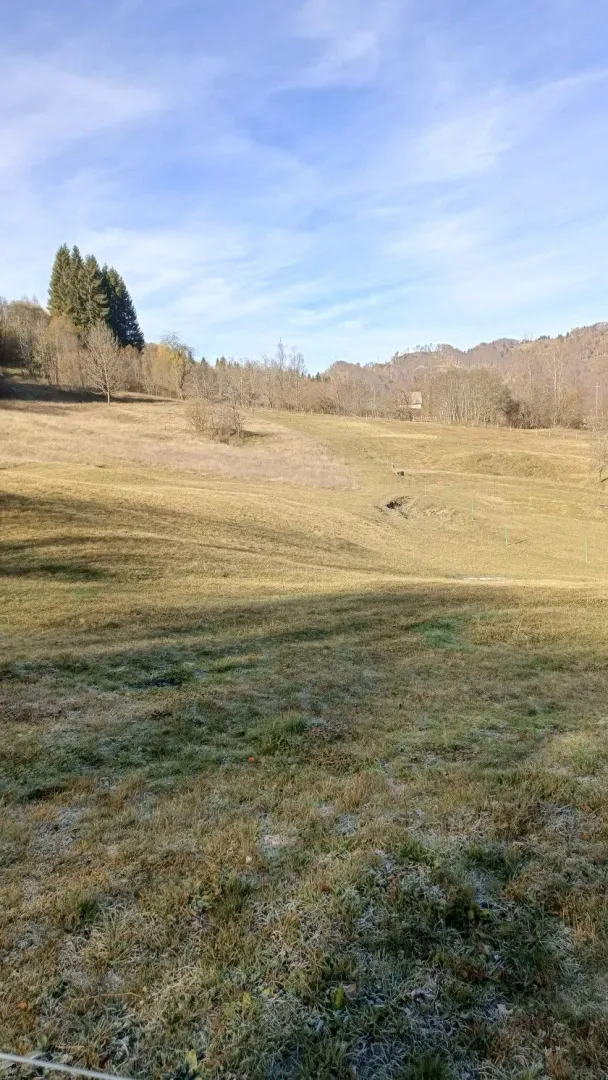 Pogled na prostranu livadu i brdoviti pejzaž prirode.