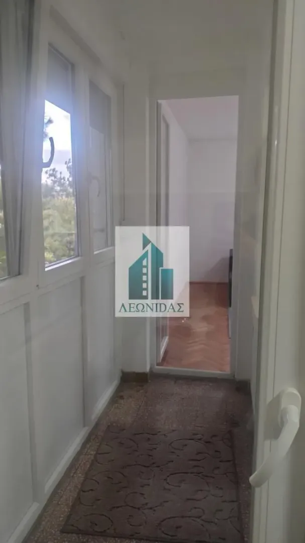 Enclosed balcony with a view of greenery and a view into the apartment's interior.