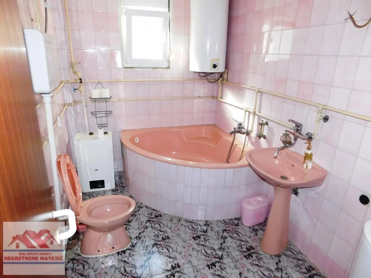 Kupatilo sa roze sanitarijama, kadom i pločicama na zidovima.