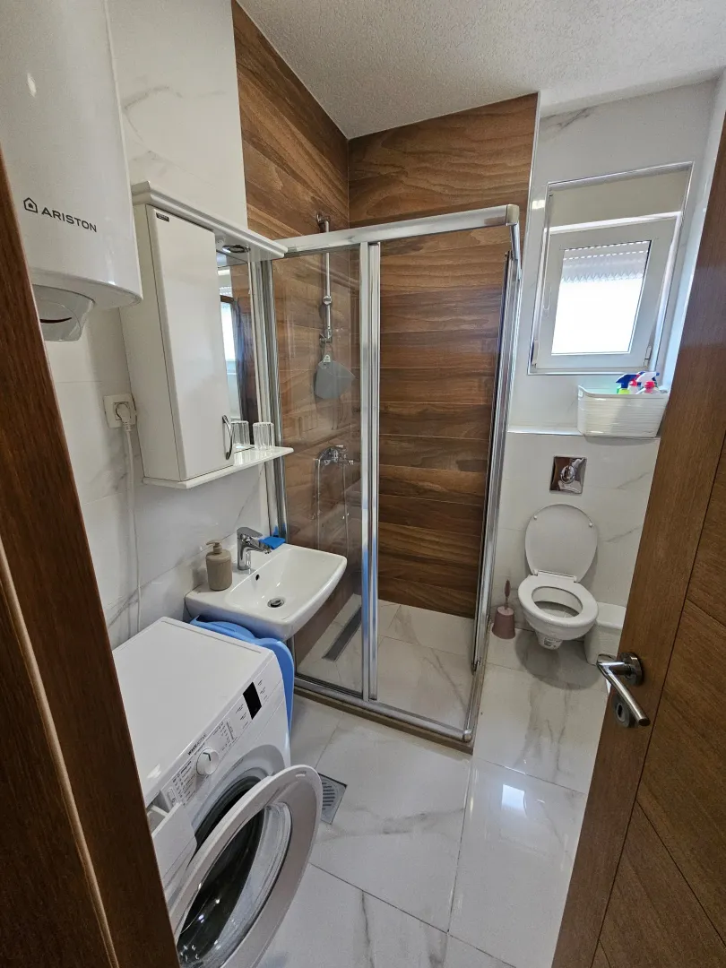 Modern bathroom with a shower cabin, washbasin, and toilet.
