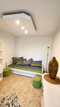 Smaller bedroom with a bed, stools, and a decorative vase. - image 8