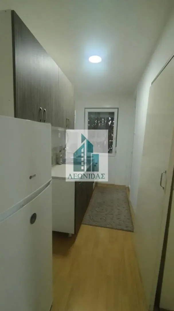 Small narrow kitchen with a white refrigerator and cabinetry.