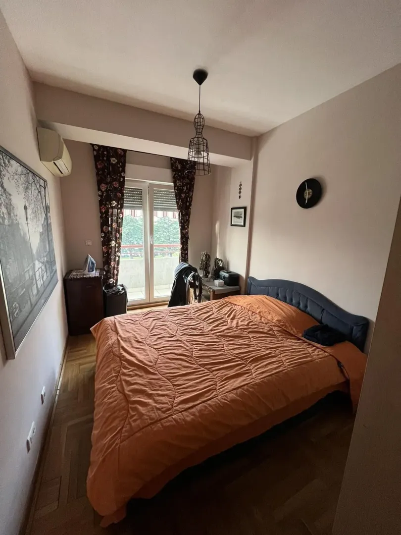 Spavaća soba sa velikim krevetom i izlazom na balkon.