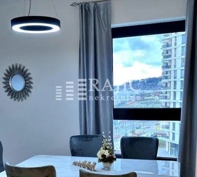 Dining area with a table, chairs, and a modern chandelier next to a window with a city view. - image 5