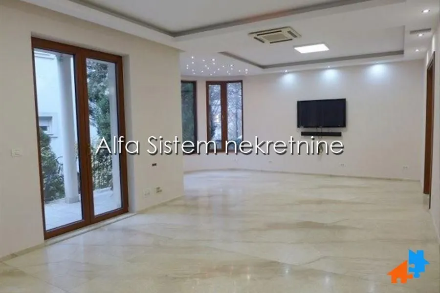 Spacious living room with large windows and tiled floors.