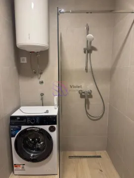 Bathroom equipped with a shower cabin, water heater, and washing machine. - image 7