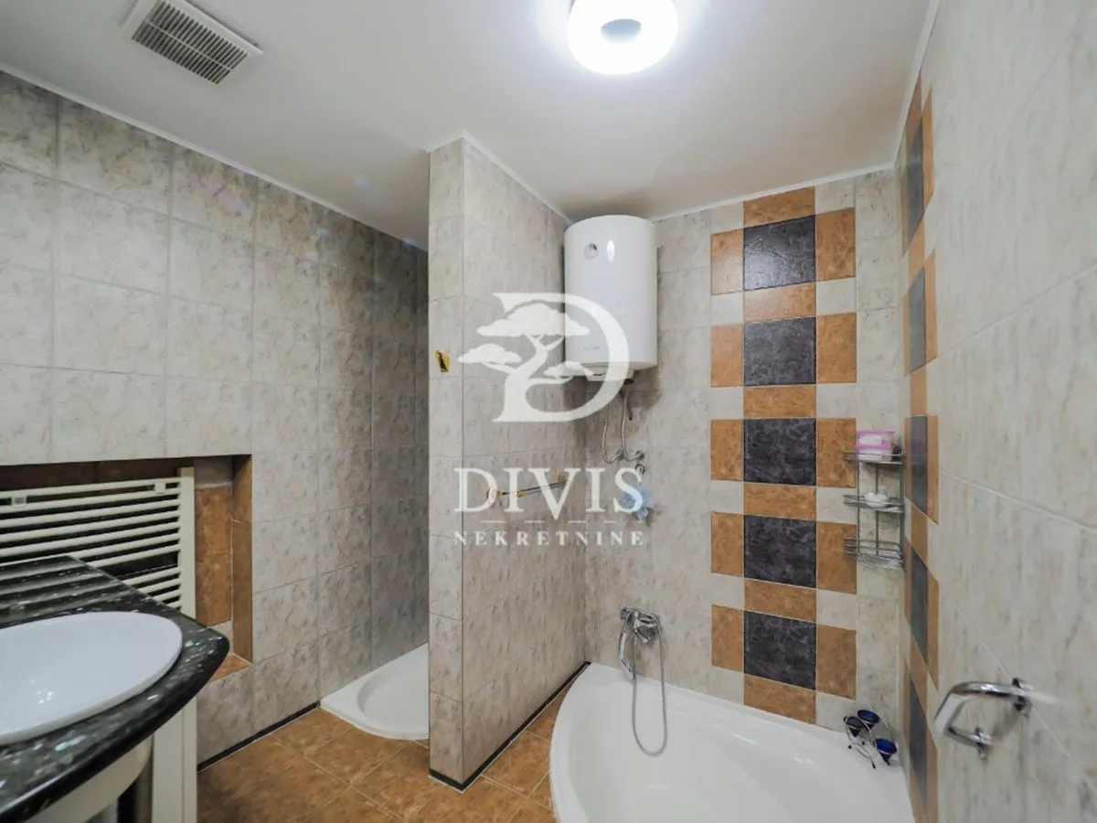 Bathroom equipped with a bathtub, shower cabin, washbasin, and water heater.