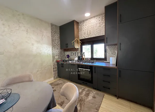Modern kitchen with dark cabinetry and a dining table in the foreground.