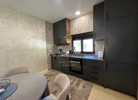 Modern kitchen with dark cabinetry and a dining table in the foreground. - image 7