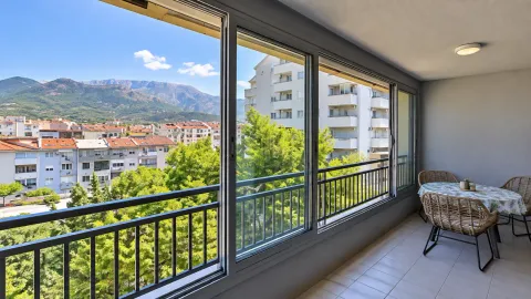 Enclosed balcony with a dining table and a view of the city and mountains. - image 7