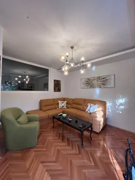 Living room with a sectional sofa, armchair, and a modern chandelier. - image 5