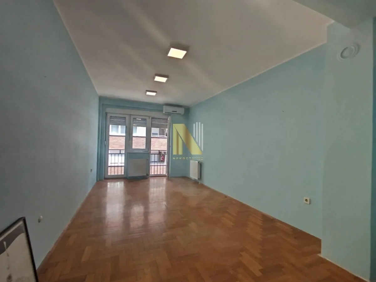 Prazna dnevna soba sa plavim zidovima, parketom i izlazom na terasu.
