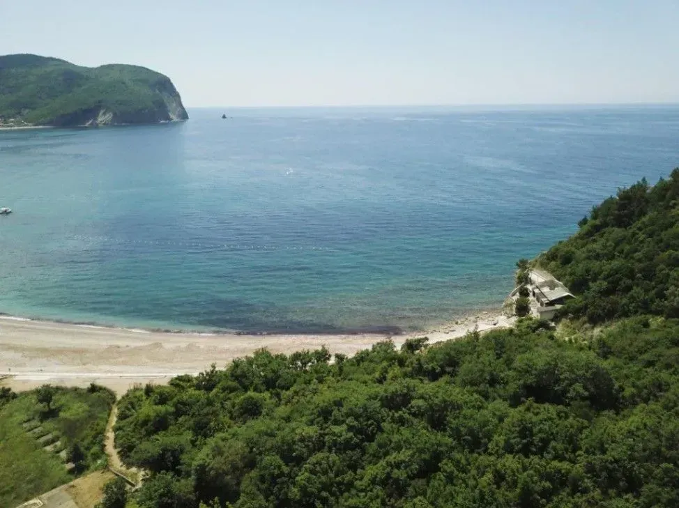 Pogled iz vazduha na more, plažu i zelenu obalu.