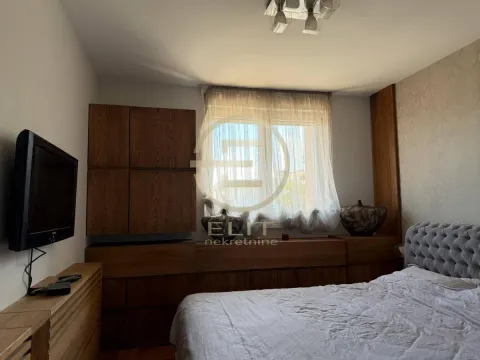 Nameštena spavaća soba sa bračnim krevetom, drvenim ormarima i televizorom na zidu. - image 24