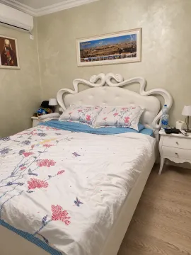Spavaća soba sa velikim bijelim krevetom, noćnim stočićima i slikama na zidu. - image 6