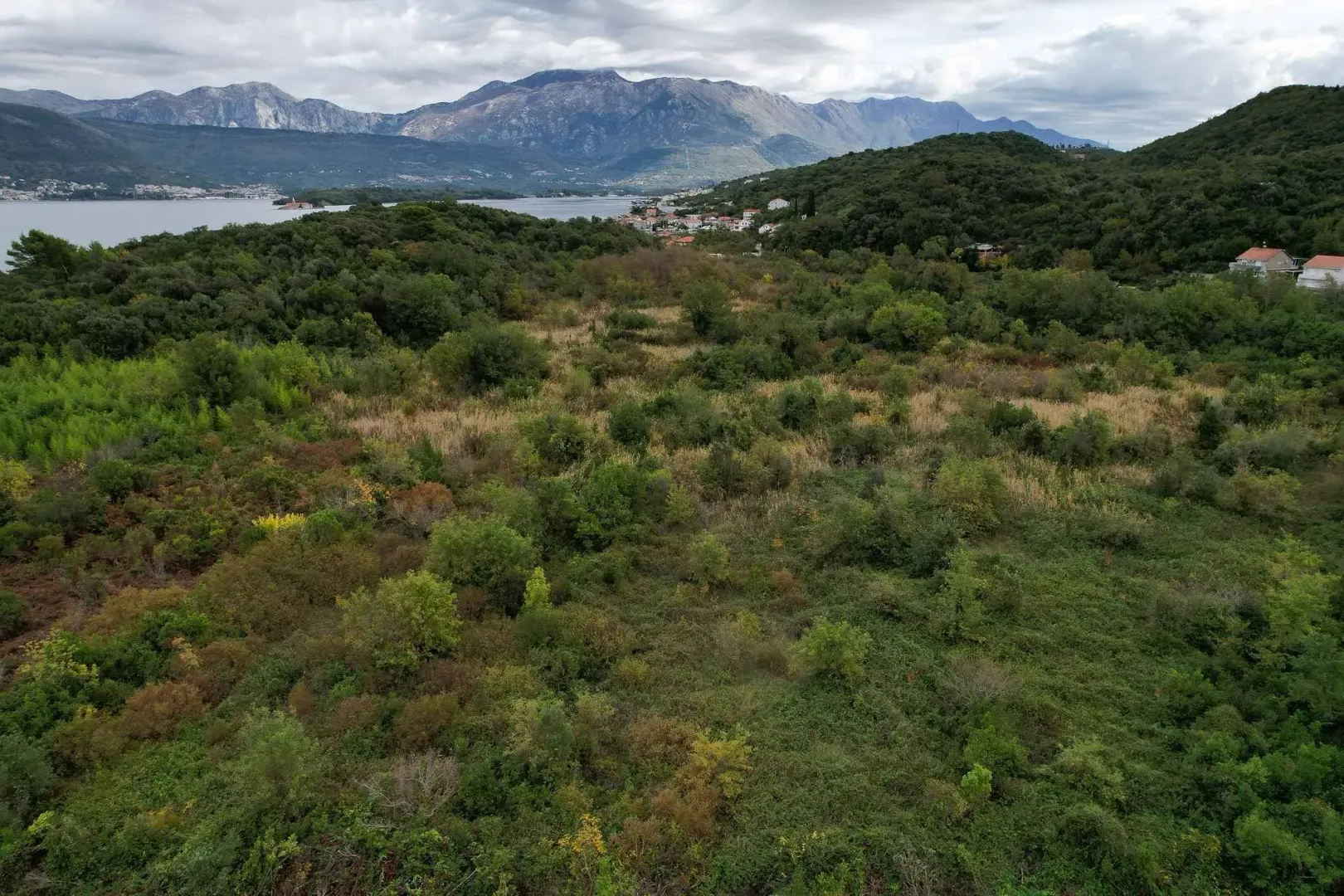 Prostrani plac okružen prirodom sa pogledom na more i planine u daljini.